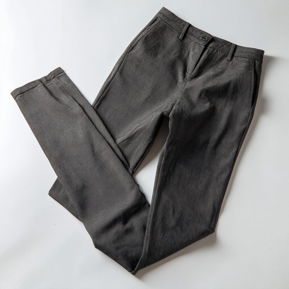 Flat lay of generic gray polyester trousers on a white background